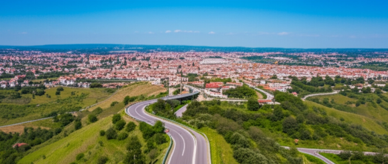 Vue aérienne d'un camion de déménagement sur une route panoramique près de Bénévent, avec la ville et les collines en arrière-plan.