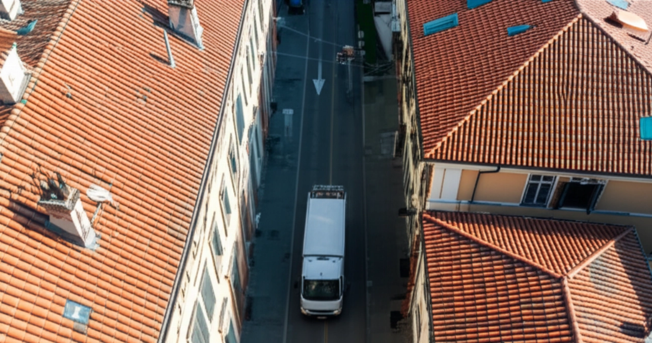 Hyperrealistische Luftaufnahme eines modernen Umzugswagens, geparkt in einer piemontesischen Stadtstraße, umgeben von historischen Gebäuden.